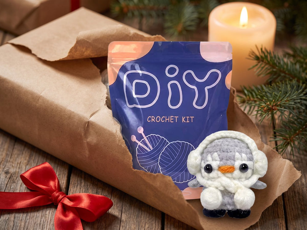 Ett halvt uppslaget paket i kraftpapper med DIY-påsen och en virkad pingvin
